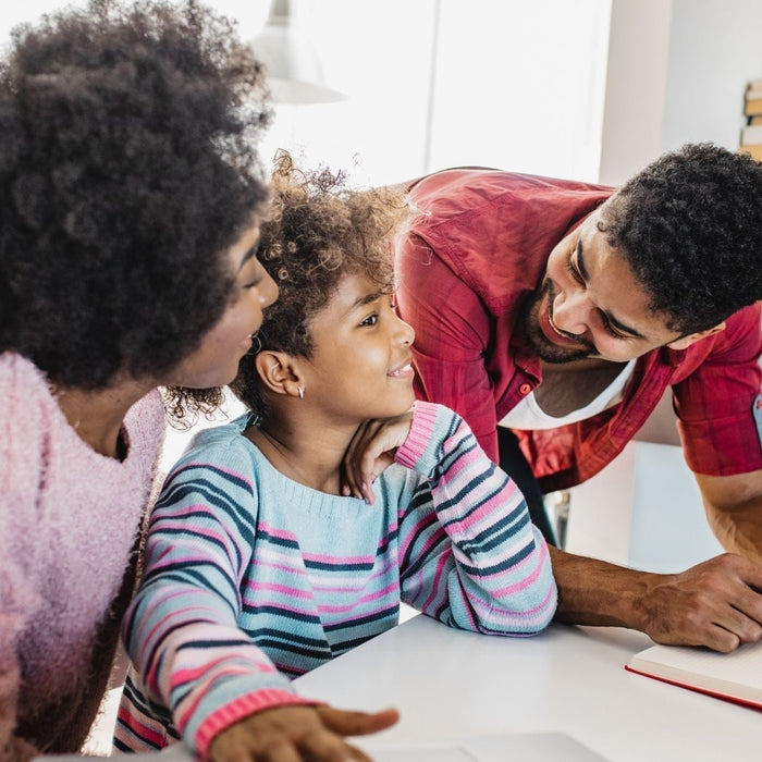 Parents helping their child study at home - supportive family encouraging focus, motivation, and learning during the end-of-year school slump.