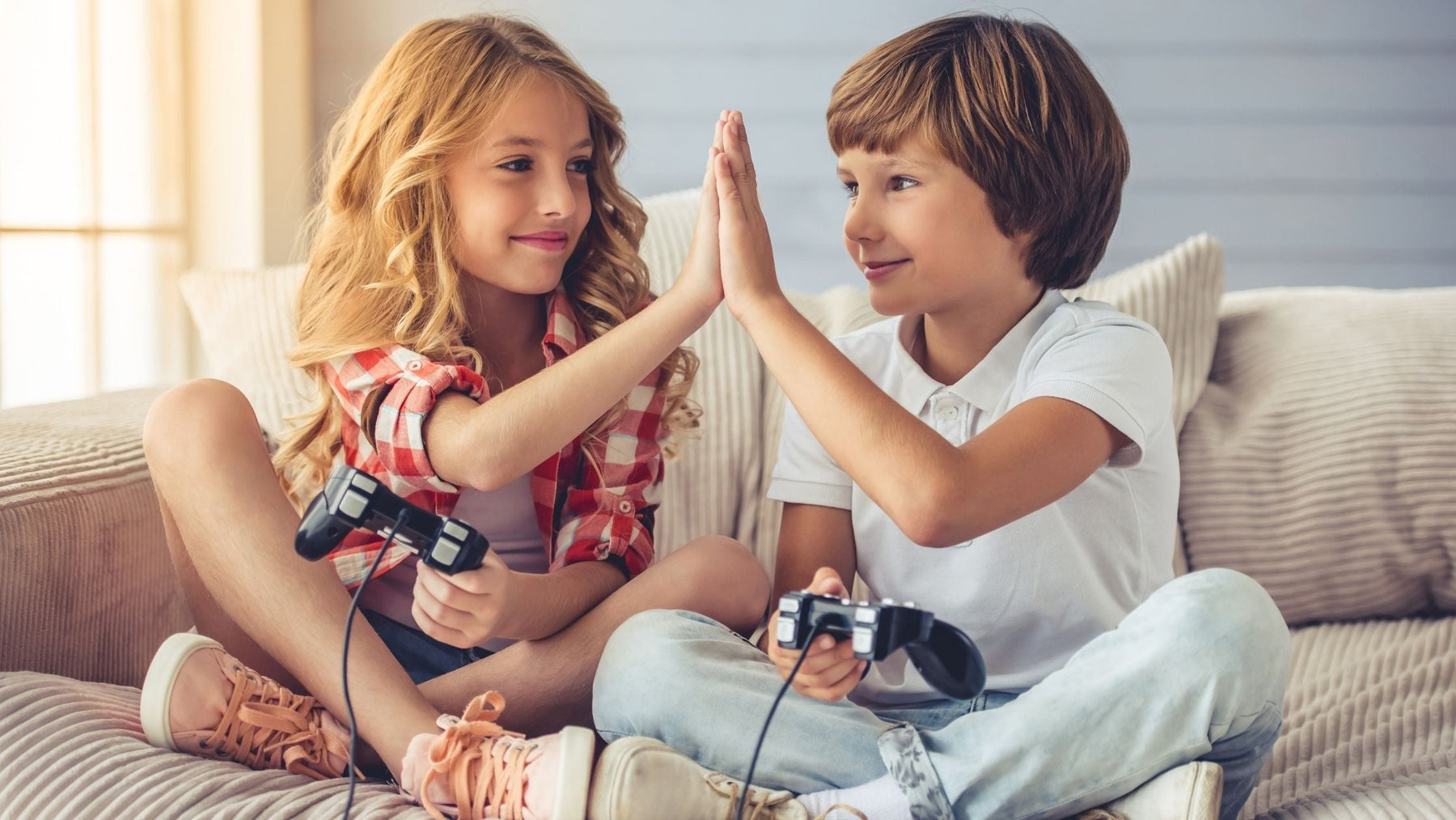 Young girl and boy smiling and high-fiving while playing video games at home, representing how ADHD can show up differently in girls and boys.