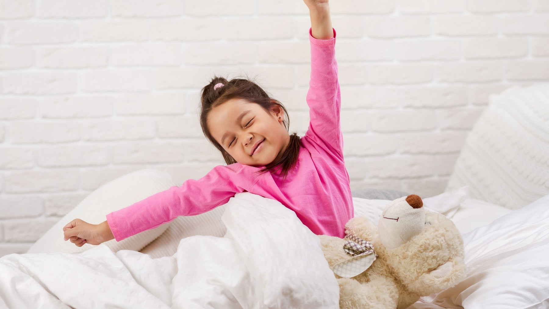 A young girl stretching and waking up refreshed in bed to start a focused school morning routine.