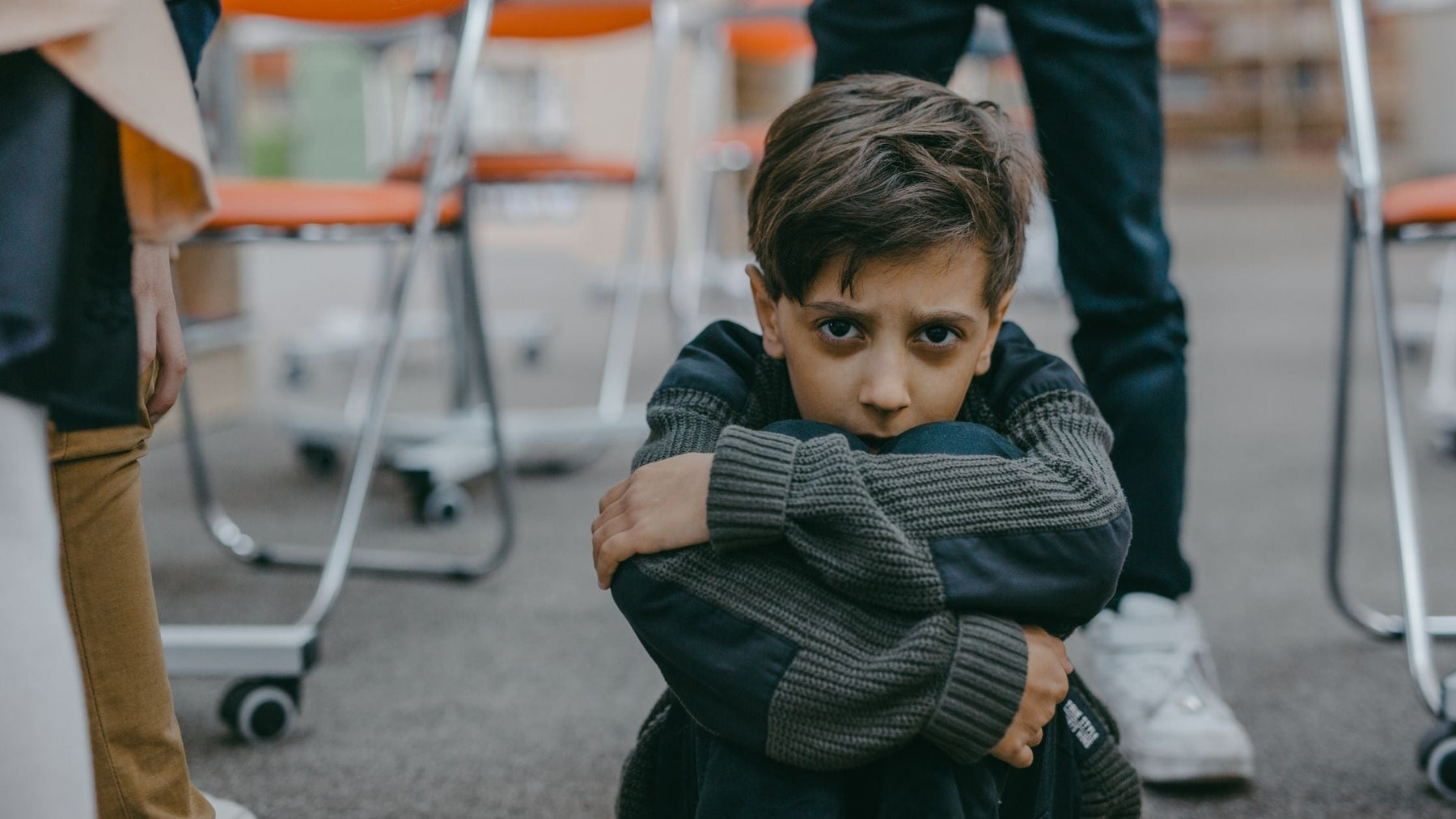 Young boy sitting on the floor with a worried expression, possibly reflecting struggles with ADHD or anxiety