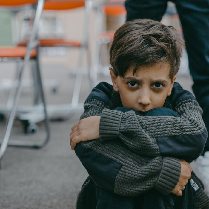 Young boy sitting on the floor with a worried expression, possibly reflecting struggles with ADHD or anxiety