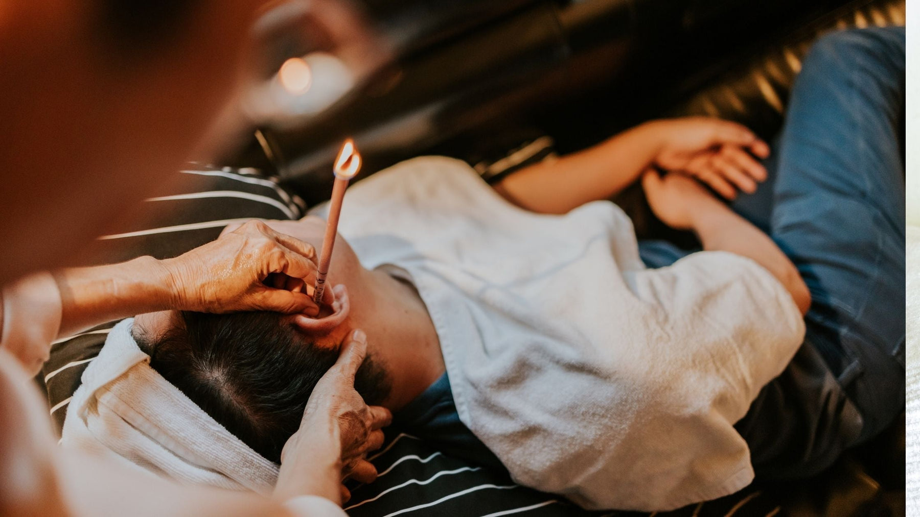 Person receiving an ear candling treatment for natural ear wellness and relaxation.