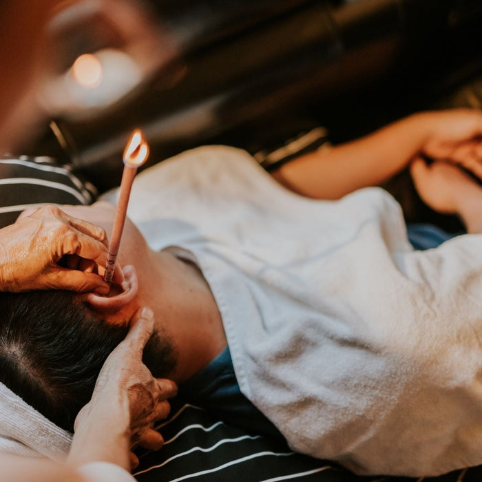 Person receiving an ear candling treatment for natural ear wellness and relaxation.
