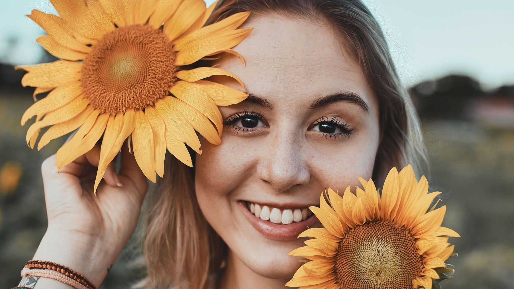 A happy woman smiling with sunflowers representing a brighter mood and recovery from burnout.