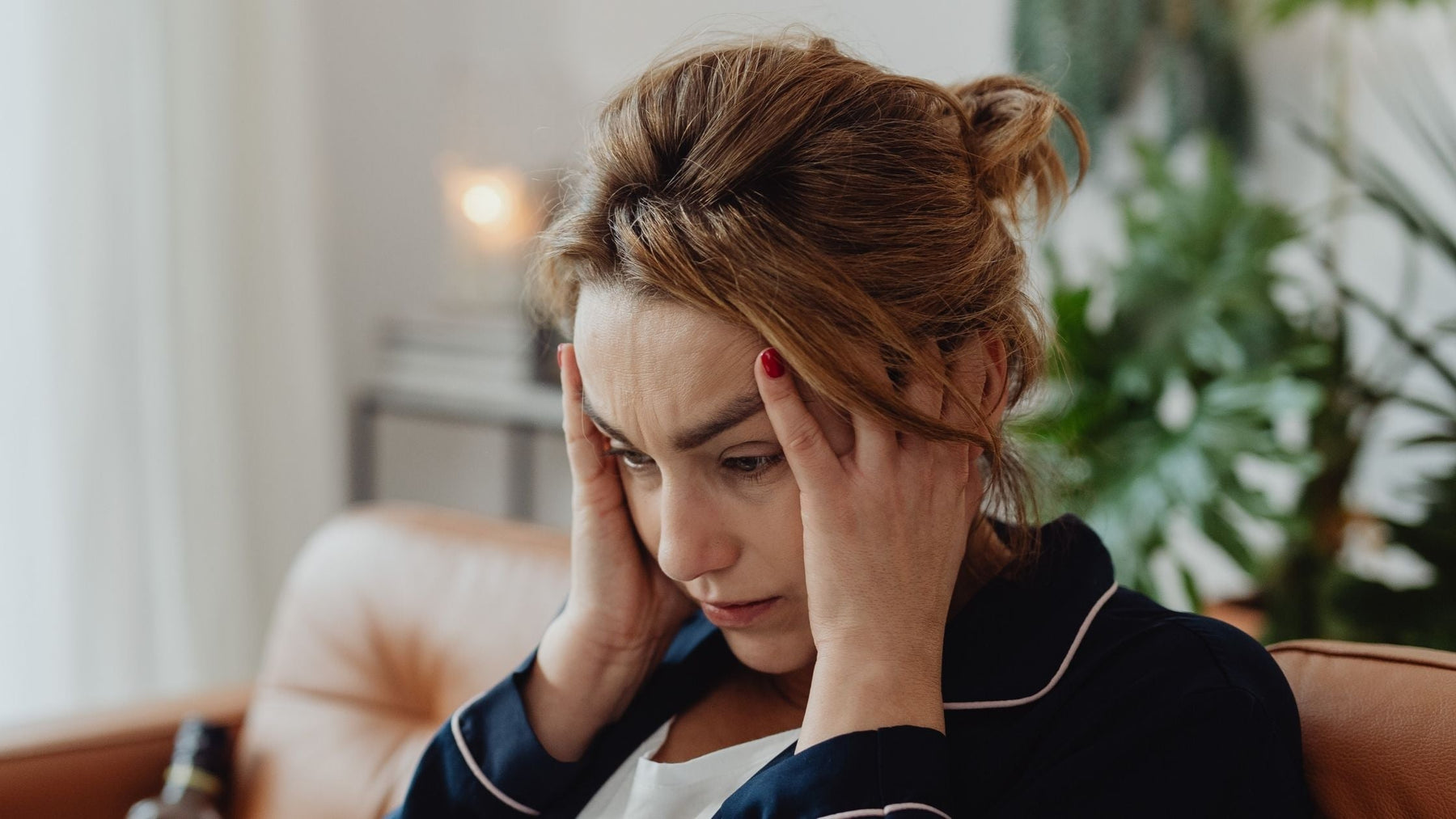 Woman holding her head, looking exhausted and distracted, suffering from brain fog