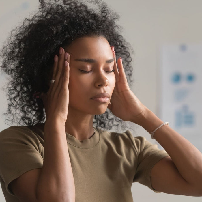 Woman experiencing signs of exhaustion with hands on her temples, representing stress, fatigue and burnout.