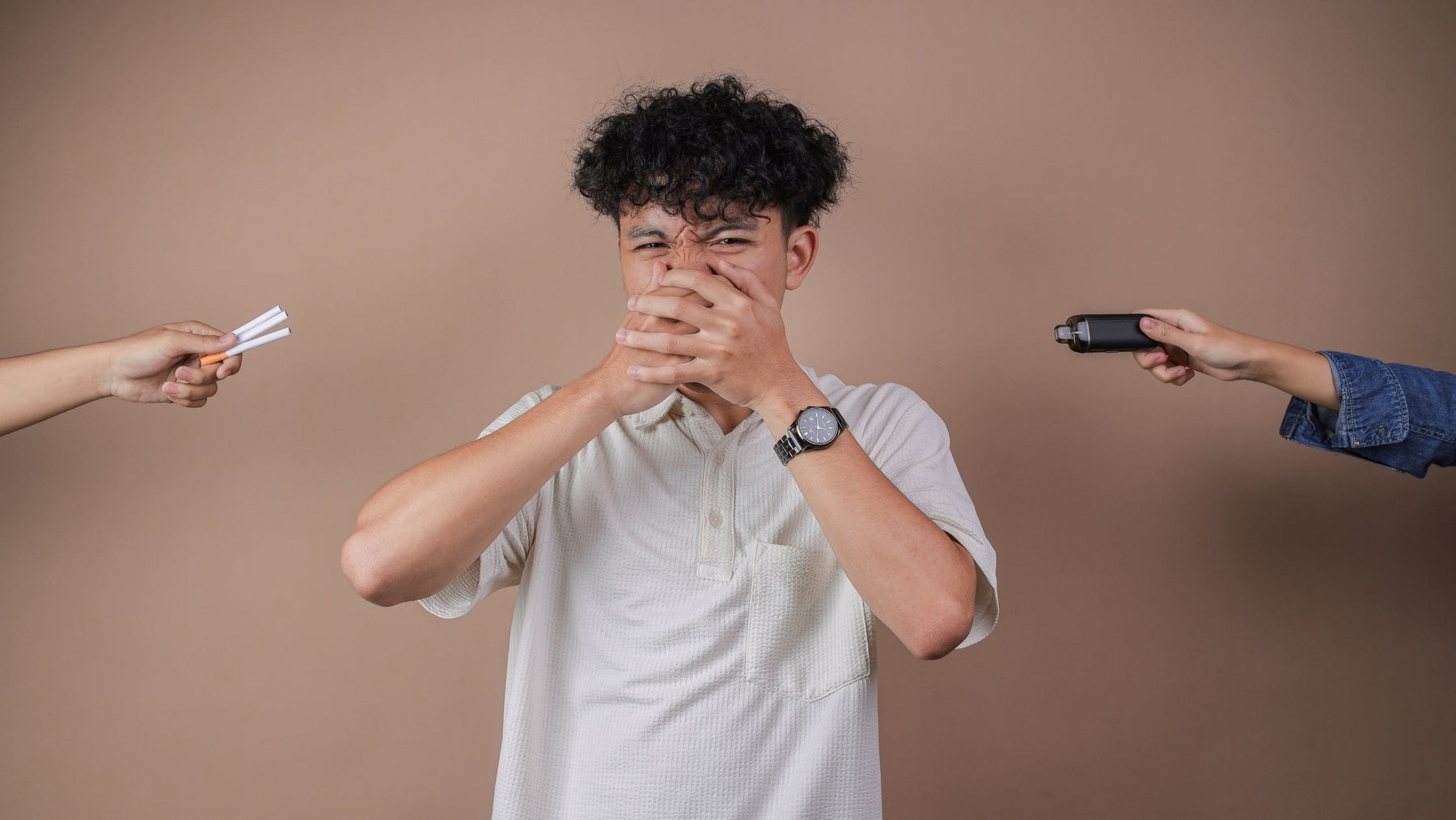 A young man covering his nose and mouth with both hands in refusal, while two hands extend from the sides of the frame offering him cigarettes on the left and a vape on the right.