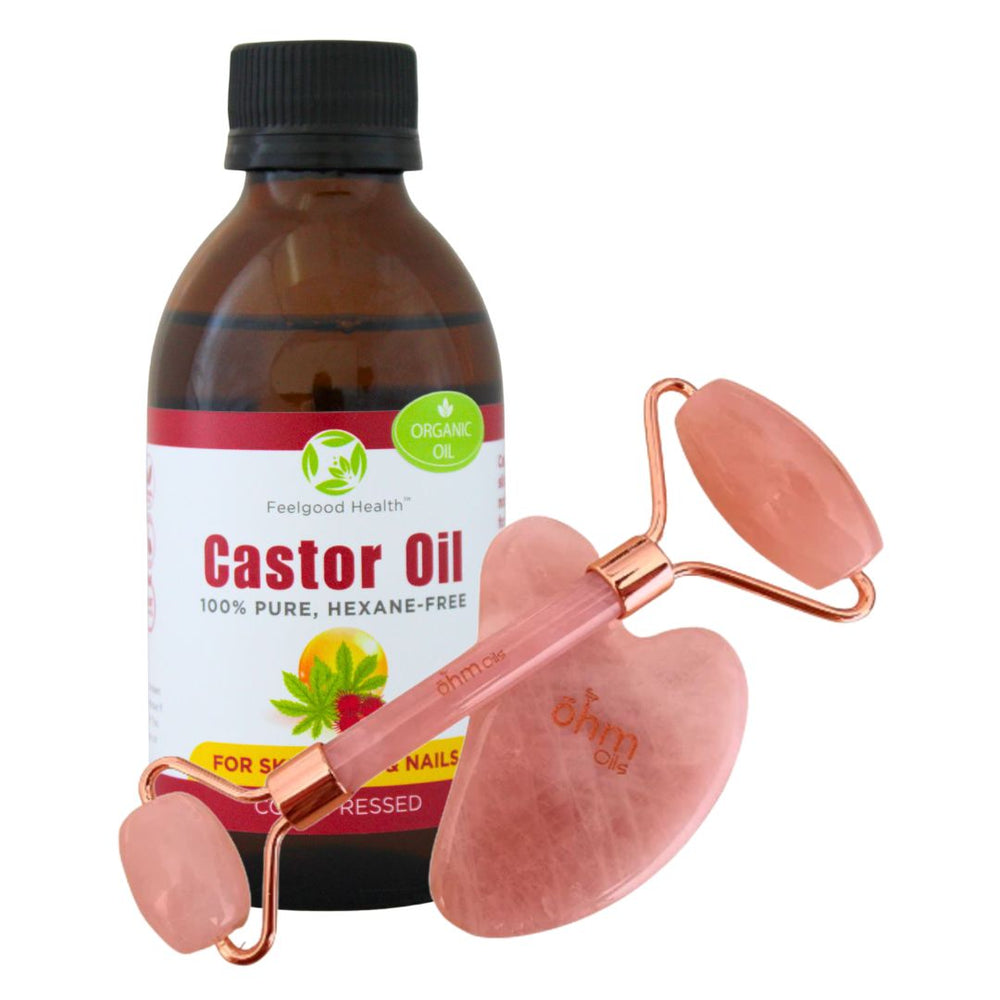 Castor oil bottle with a pink rose-quartz face roller and gua sha tool.